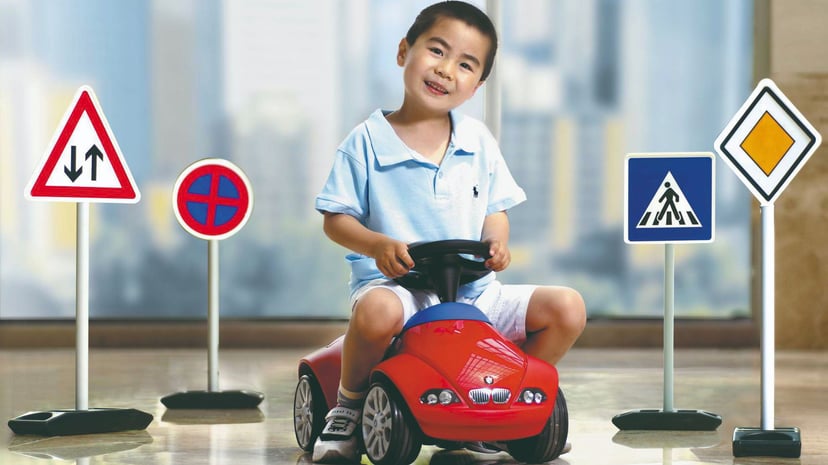 Chin Kid On Toy Bmw Amidst Small Traffic Signs Fotor Crop
